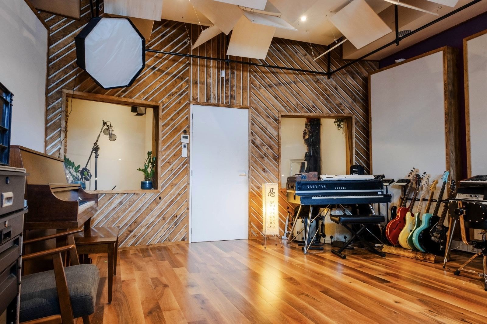 Live room met houten wand, gitaren en piano bij Sound City Amsterdam